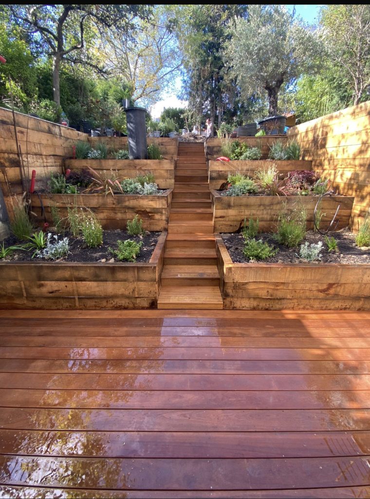 Vue finale de la création paysagère à Grosrouvre avec escalier central et massifs en bois intégrés dans la pente.