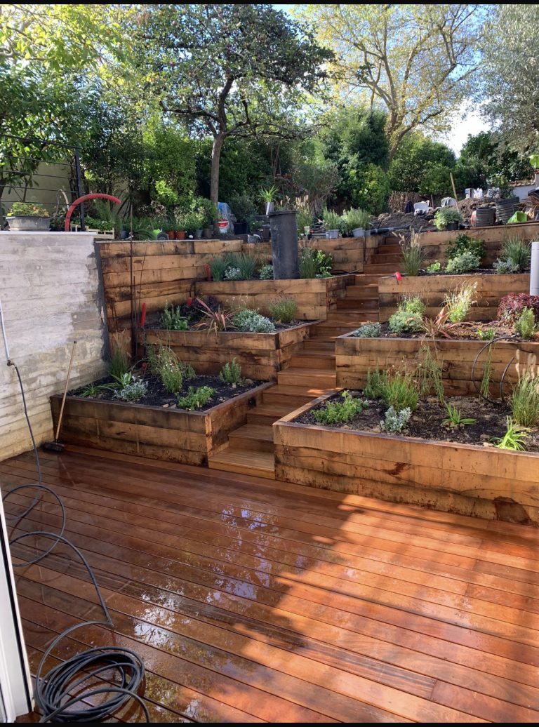 Après travaux, nous avons créé une terrasse en bois avec des massifs paysagers en paliers pour structurer le jardin à Grosrouvre.